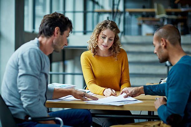 A group of people are sitting around a table looking at papers.
