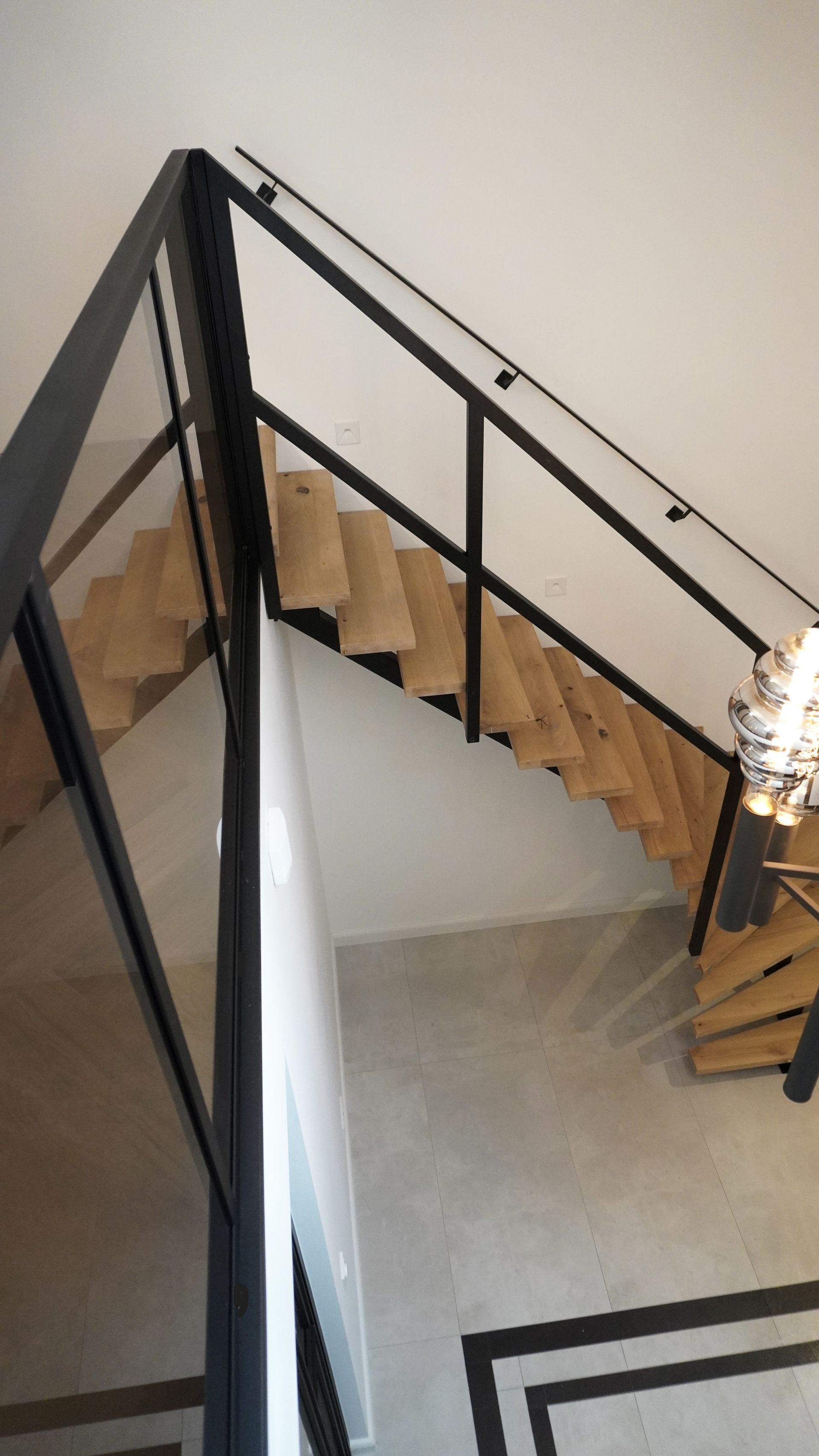 Middenboom stalen trap met eikenhouten treden stalen trapleuningen en stalen balustrade met glas