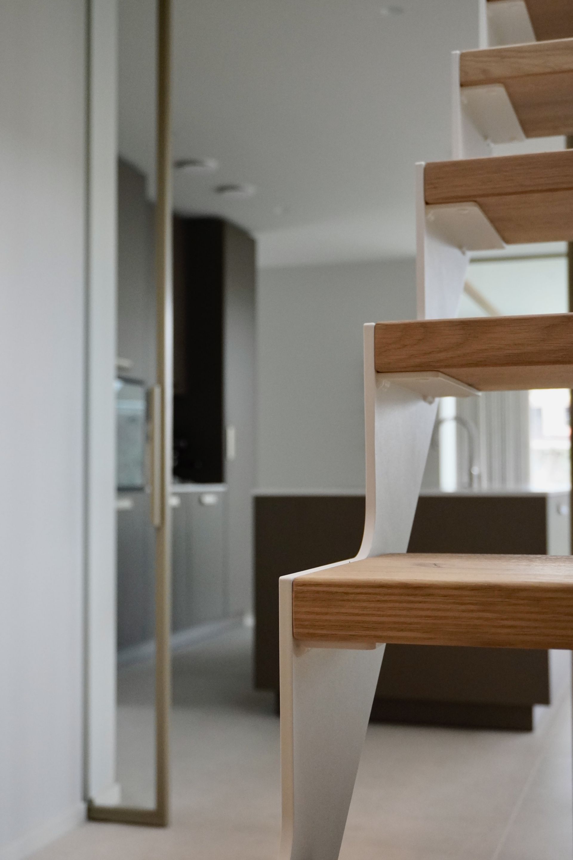Witte stalen trap strak design met licht eiken treden op maat gemaakt door Hollemans Homesteel uit Numansdorp