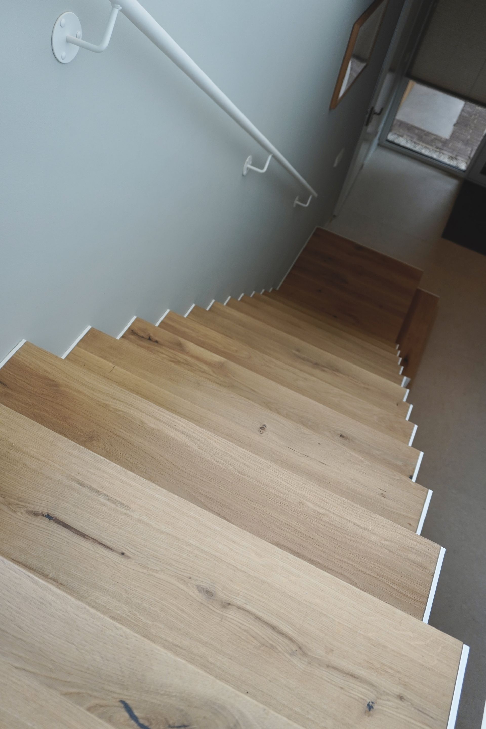 Witte stalen trap strak design met licht eiken treden op maat gemaakt door Hollemans Homesteel uit Numansdorp
