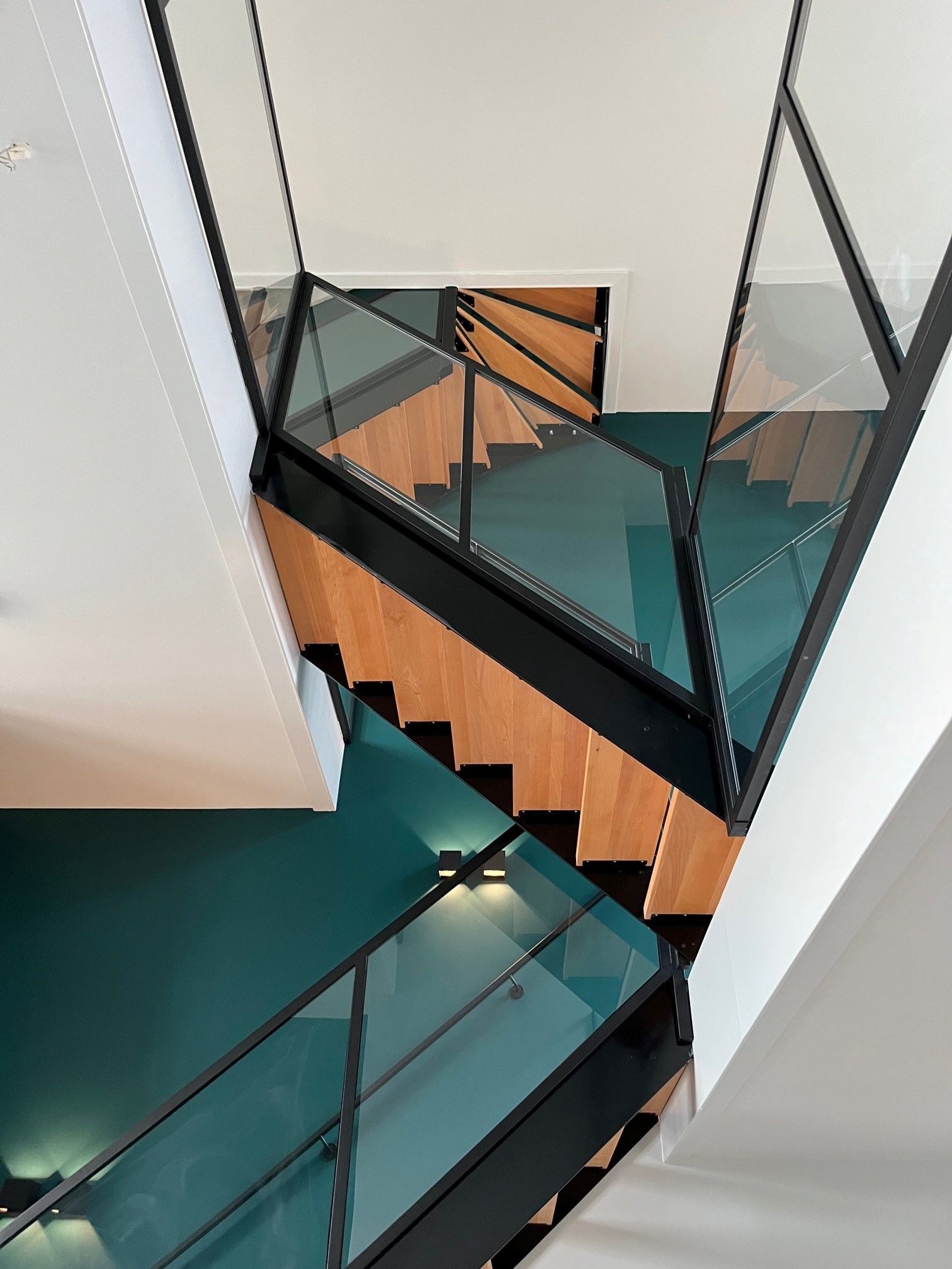 Stalen maatwerk trap met eikenhouten treden en glazen balustrade door Hollemans Homesteel uit Numansdorp