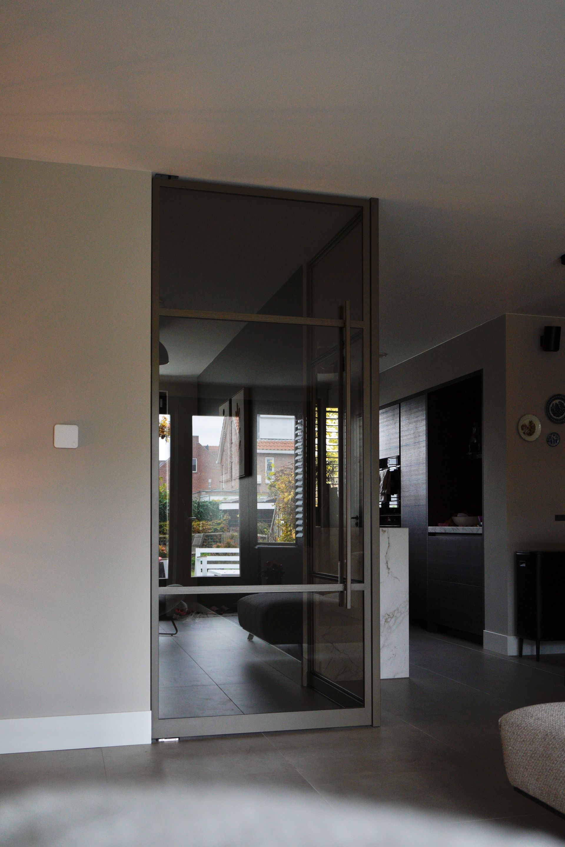 Glazen deur met metalen frame in een modern interieur, met uitzicht op de tuin.
