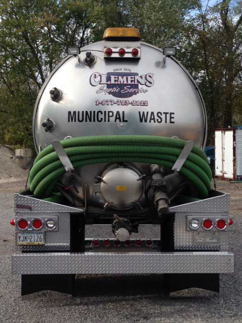 A municipal waste truck is parked in a parking lot