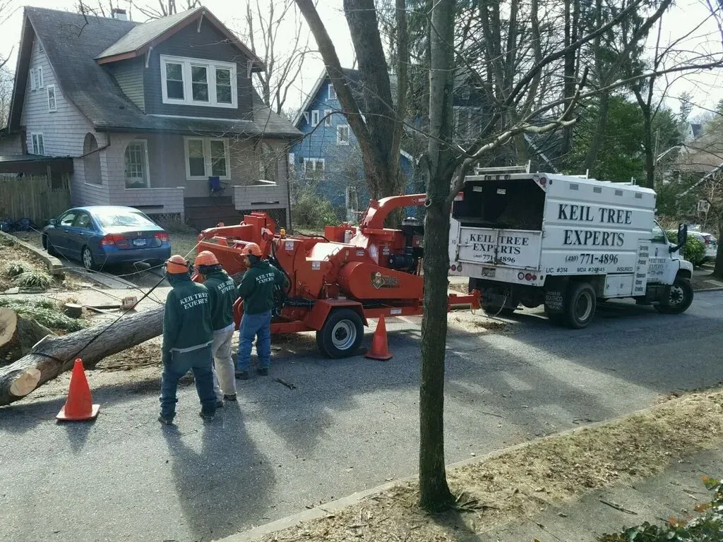 Utility crew with red equipment truck working beside a house on a suburban street