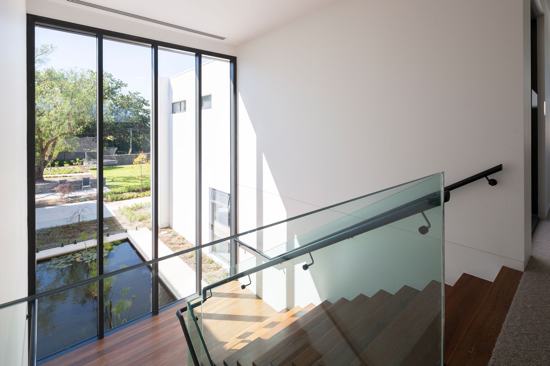 A staircase with a glass railing and a large window