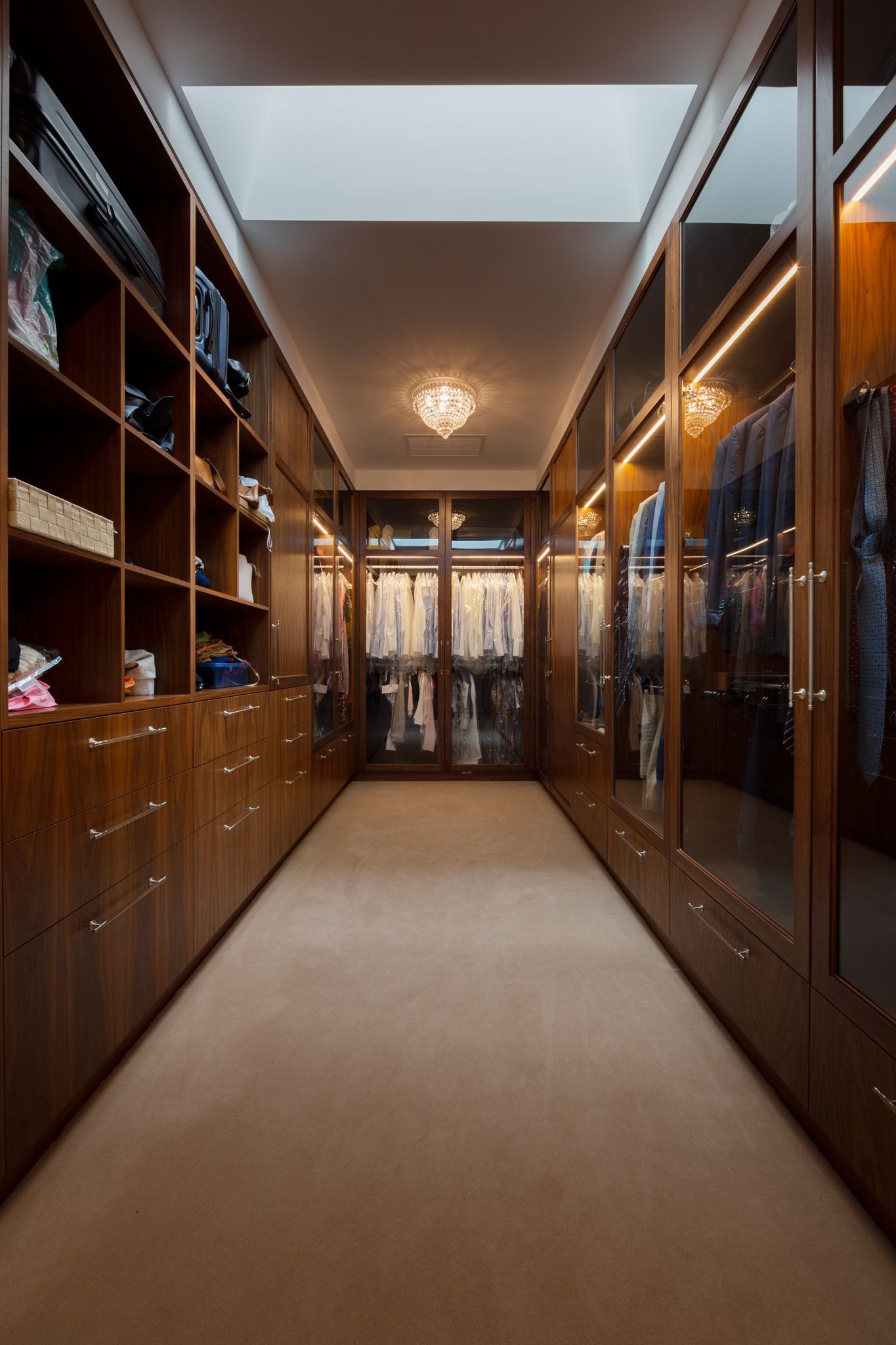 A long walk in closet with lots of shelves and drawers.