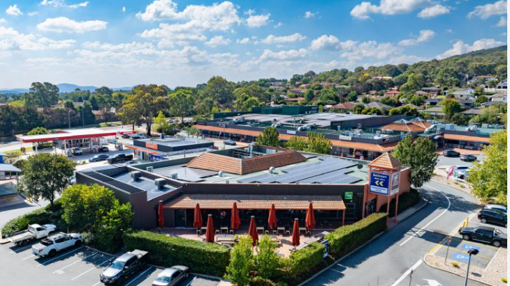 An aerial view of a shopping center with a lot of cars parked in front of it.