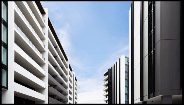 Looking up at a row of tall buildings with a blue sky in the background