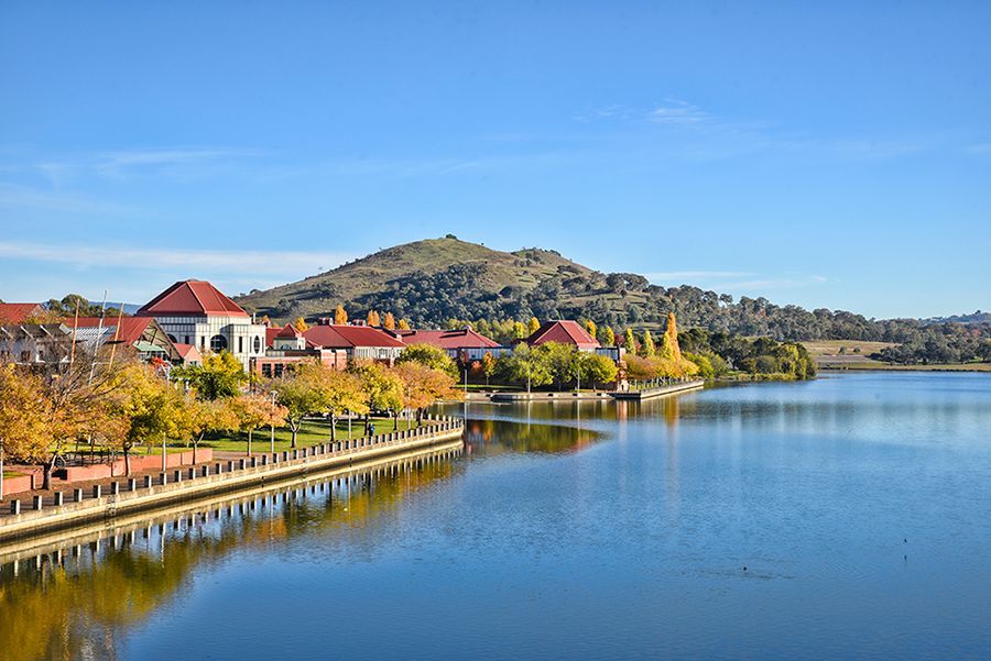 A lake with houses on the shore and a mountain in the background.