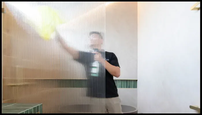 A person is cleaning a wall with a spray bottle and a cloth.