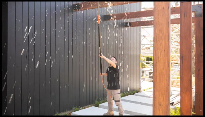 A person is cleaning a wall with a spray bottle and a cloth.