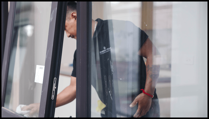 A man is cleaning a window with a cloth.
