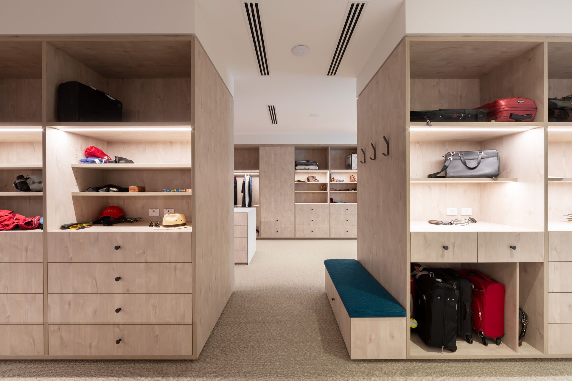 A walk in closet with lots of shelves and drawers filled with luggage.