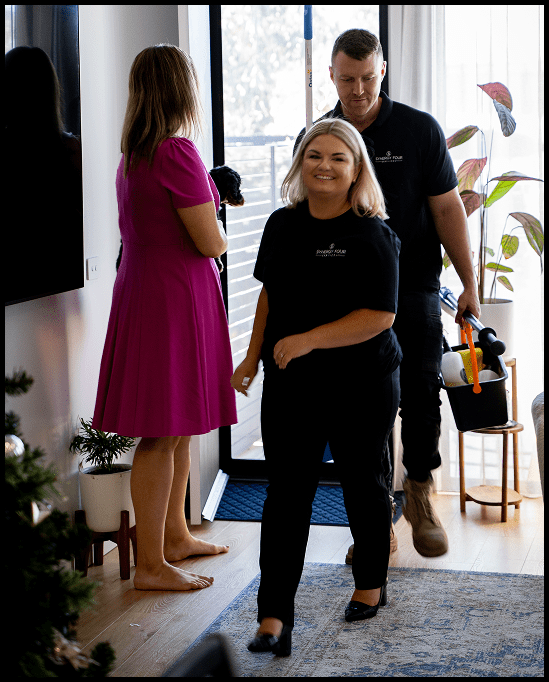 Smiling Airbnb cleaning team meeting with a property owner at the door, ready to begin turnover service