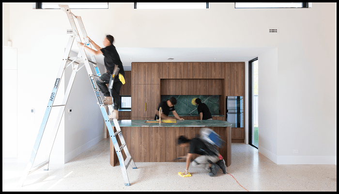 Cleaning crew performing detailed Airbnb turnover cleaning in a modern kitchen, including high surfaces and countertops