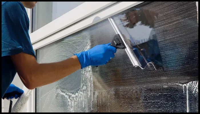 Professional cleaner using a squeegee to clean a large window during an end-of-lease cleaning
