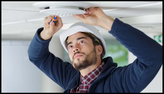 Professional installing a smoke detector as part of fire safety measures