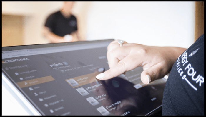 Close-up of a Synergy Four Services staff member using a touchscreen to manage cleaning projects.