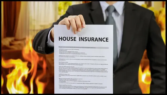 Person holding a house insurance document with fire in the background, emphasizing fire safety preparedness.
