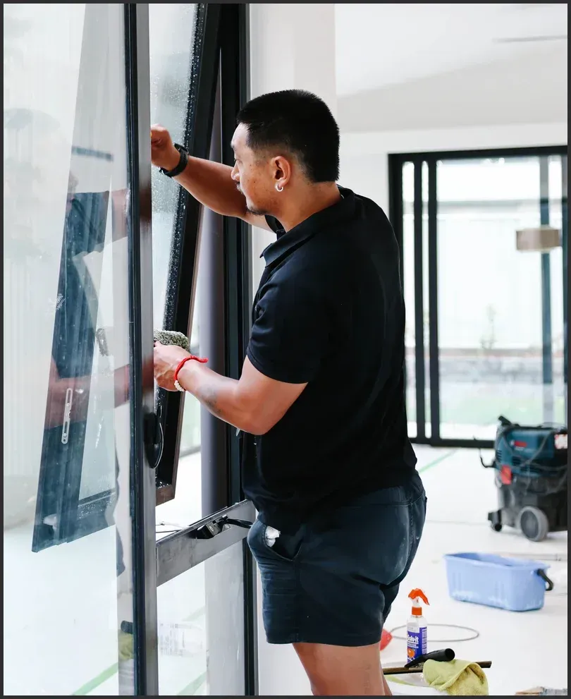 Professional cleaner washing a glass window during a pre-sale home cleaning.
