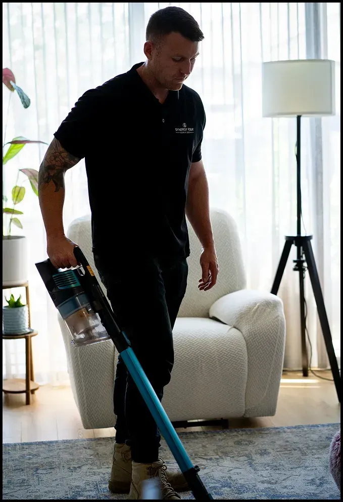 Professional cleaner vacuuming a living room during a pre-sale home cleaning.