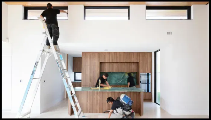 Professional cleaners performing end-of-lease cleaning in a modern kitchen, including floor scrubbing and window cleaning