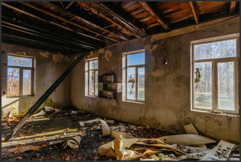 Severely fire-damaged room with a collapsed ceiling and soot-covered walls