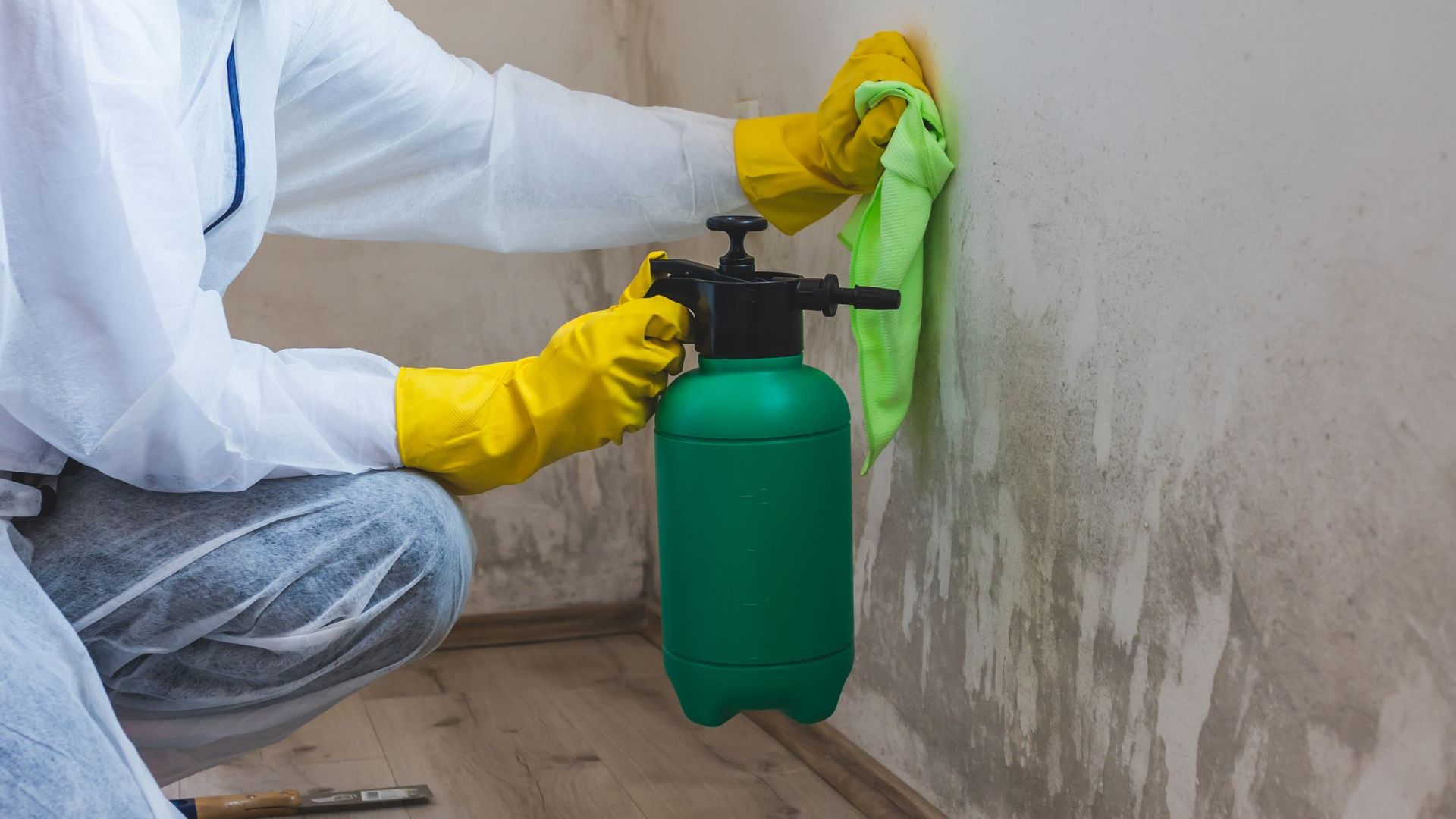 A person is cleaning a wall with a spray bottle and a cloth.