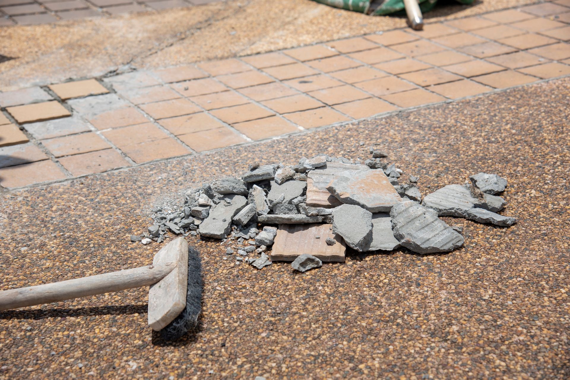 A pile of bricks and a broom on the ground.