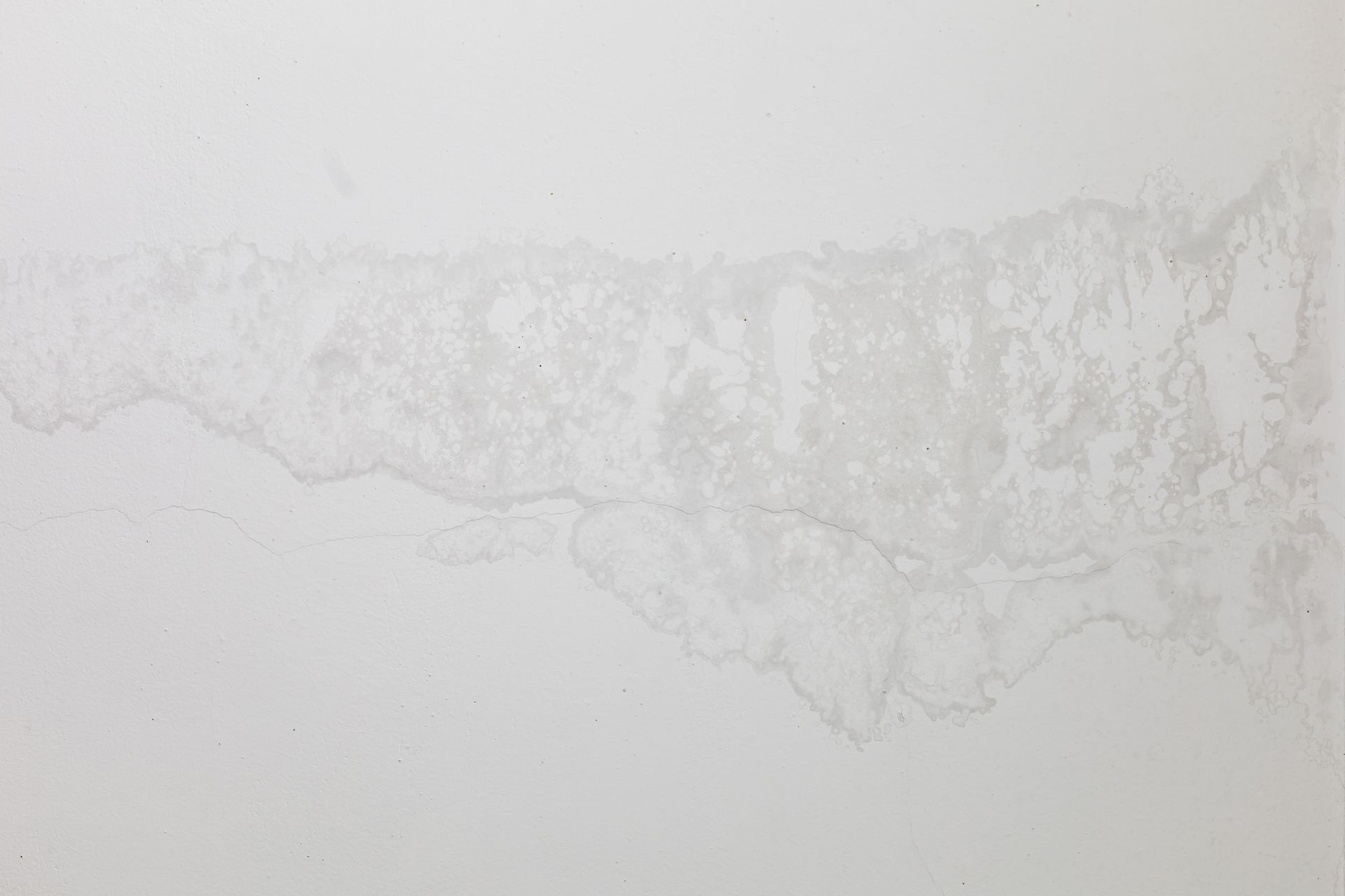 A close up of a white wall with a stain on it.