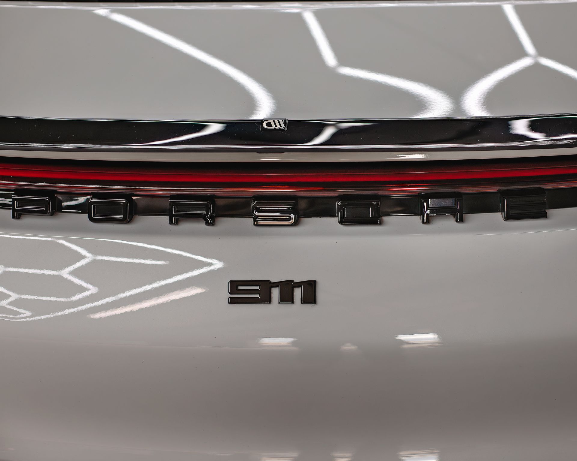 Close-up of a white 3M device with a glossy black top and red stripe, showing black clips underneath.