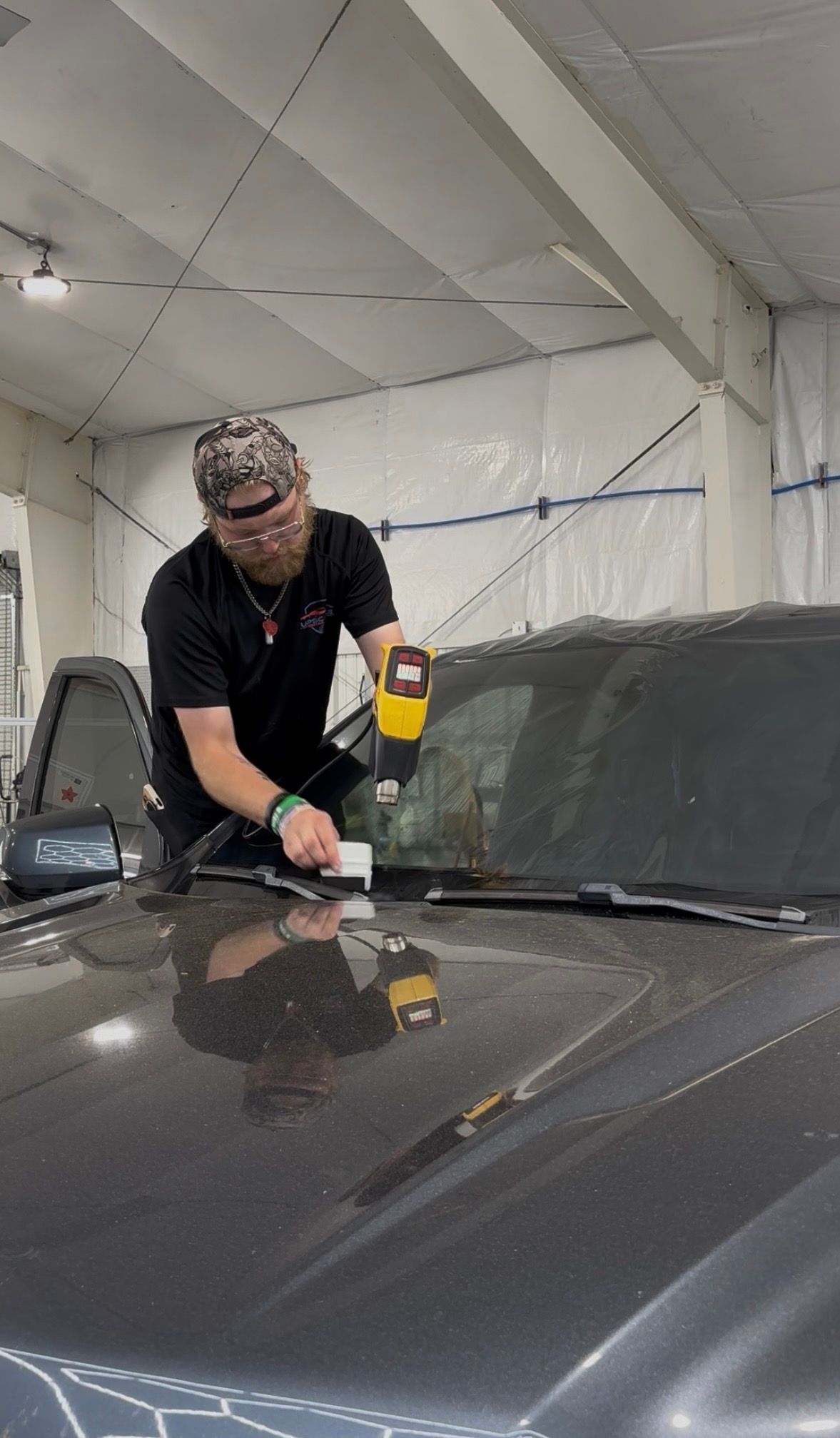 Technician polishing a white car in an auto detailing workshop