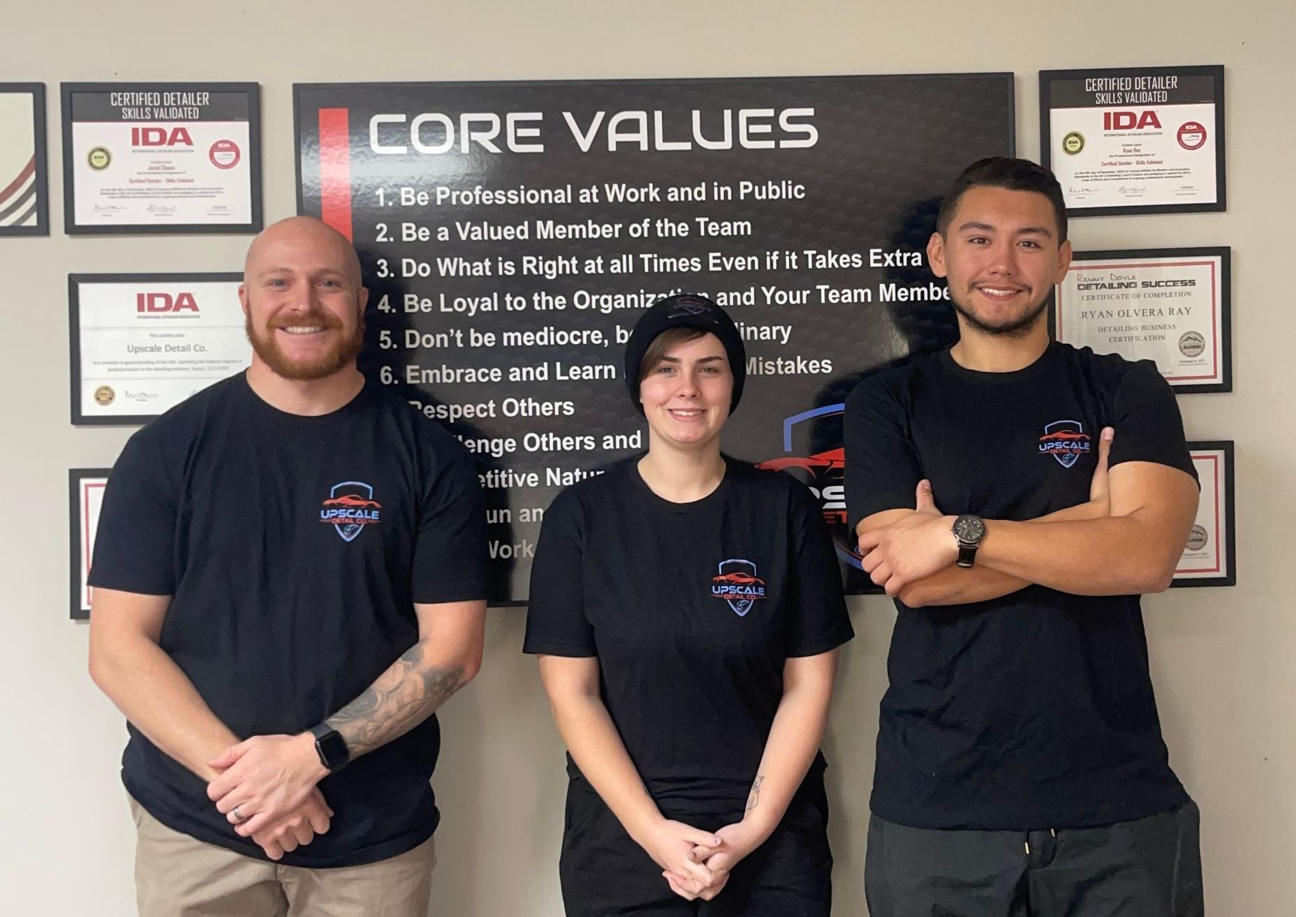 Three people standing in front of a sign that says core values