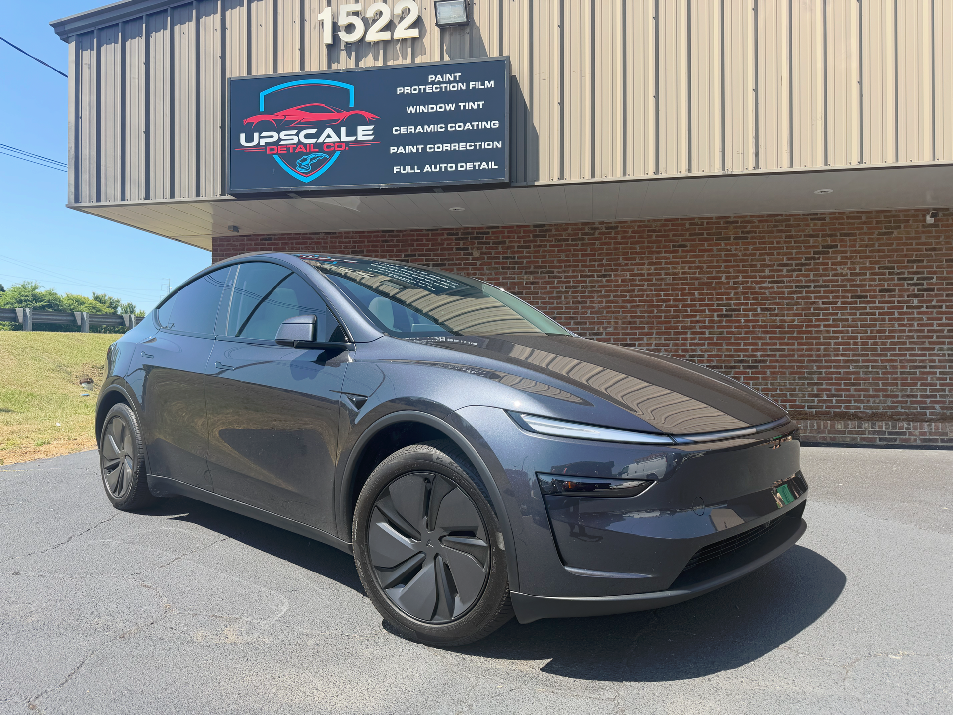 Black Tesla SUV parked outside an Upscale sign on a brick building