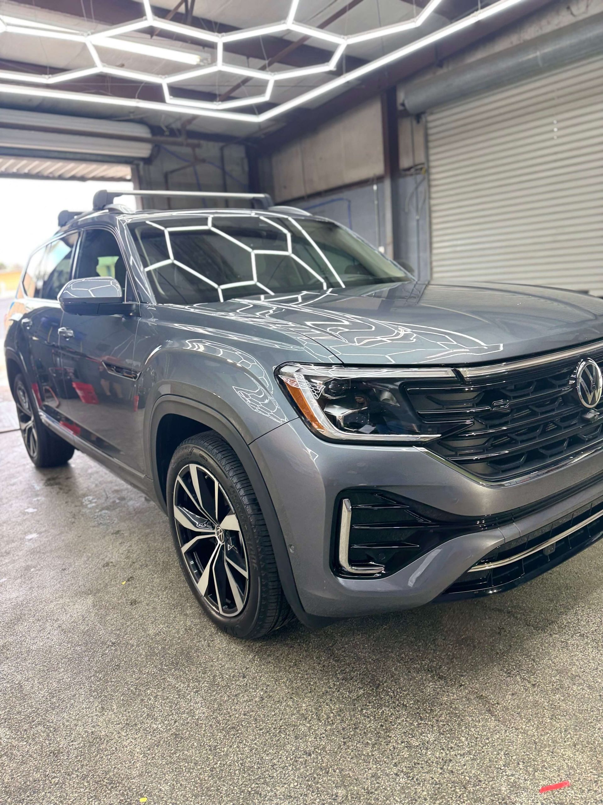 Gray Volkswagen SUV inside a garage, under hexagonal LED lights.