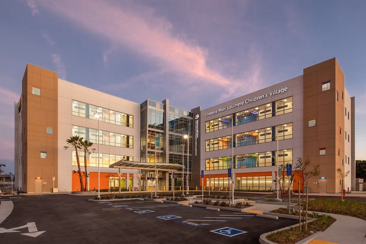 Modern brick-and-glass office building at dusk with lit windows and a glass entrance lobby