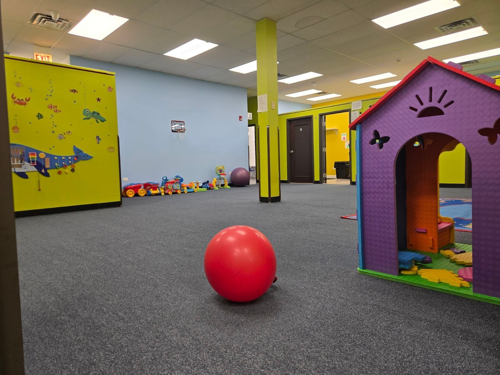 Colorful indoor playroom with a red ball on carpet and a purple playhouse on the right