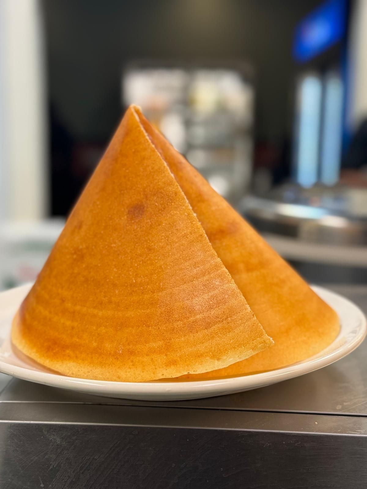 Two golden triangular cakes on a white plate, served on a table in a blurred indoor setting