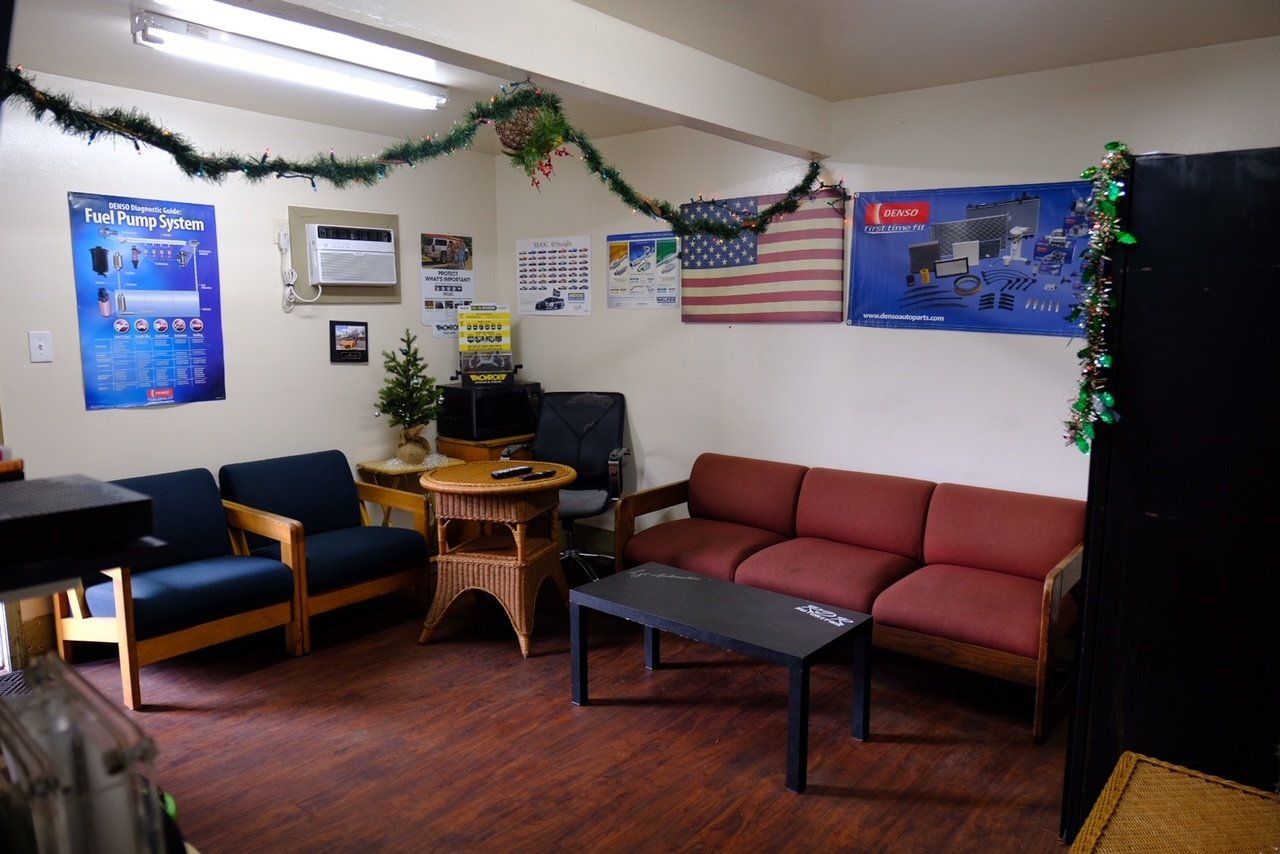 Waiting room with chairs, red couch, coffee table, wall posters, and decorative plants.