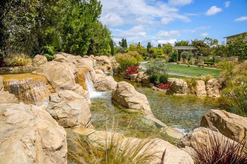 A waterfall is surrounded by rocks and trees in a park.