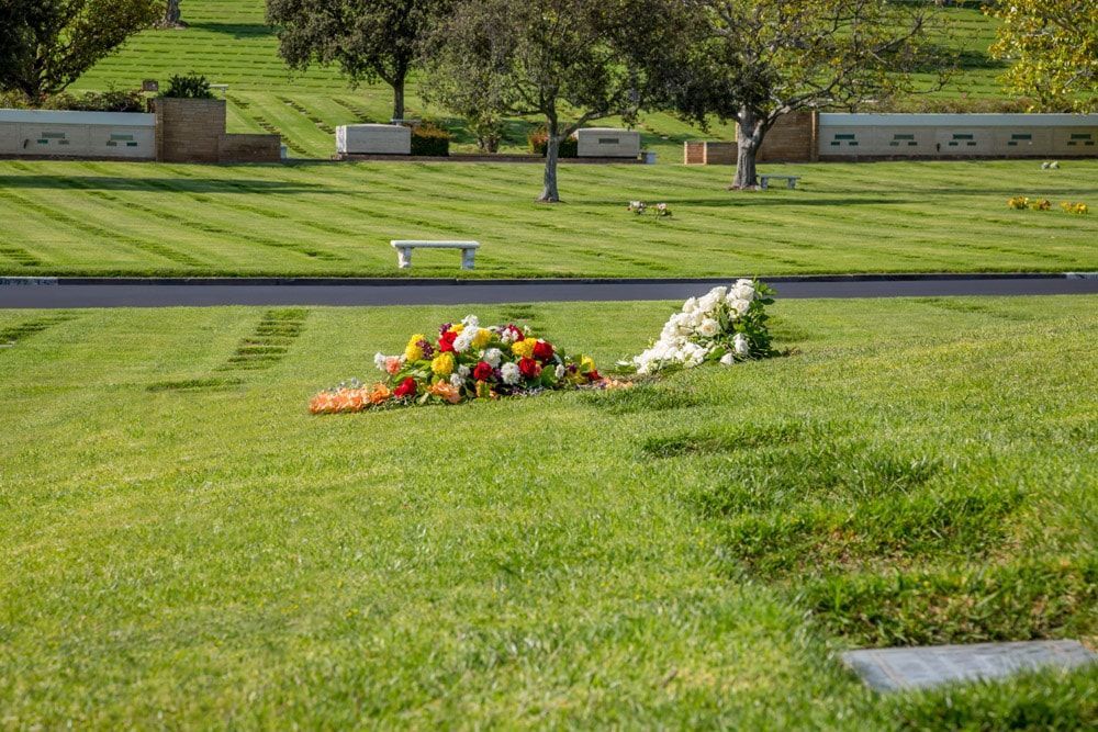 A cemetery with a bunch of flowers on the ground.