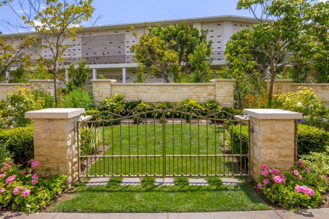 There is a gate in the middle of a lush green garden.
