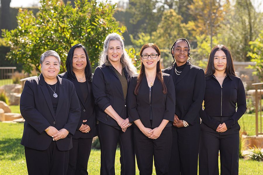 A group of women in black suits are posing for a picture.