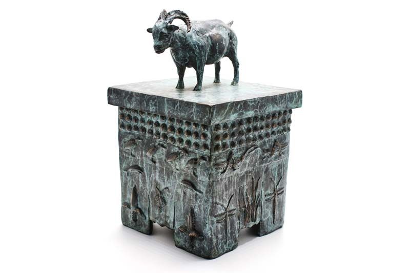 A statue of a goat standing on top of a box.