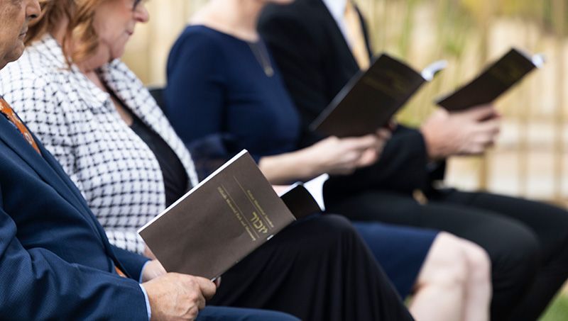 A group of people are sitting in a row reading program for memorial services