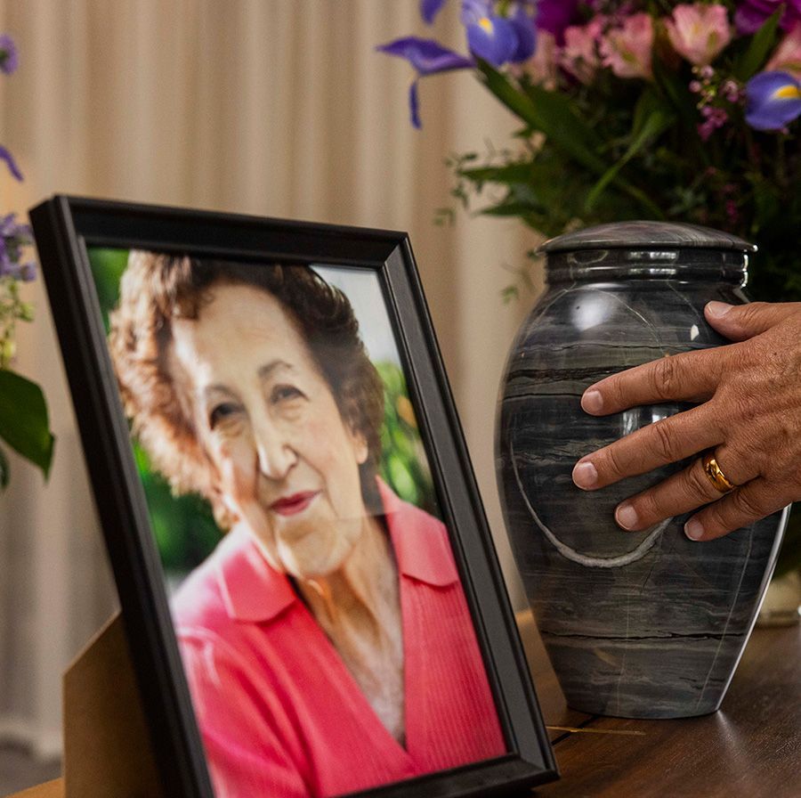 A man is putting a picture of an elderly woman in an urn.