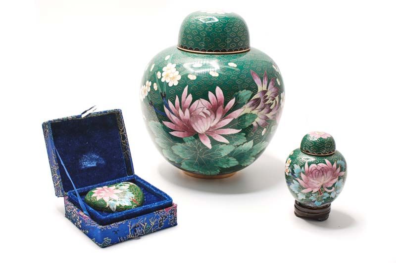 A green vase with pink flowers and a blue box