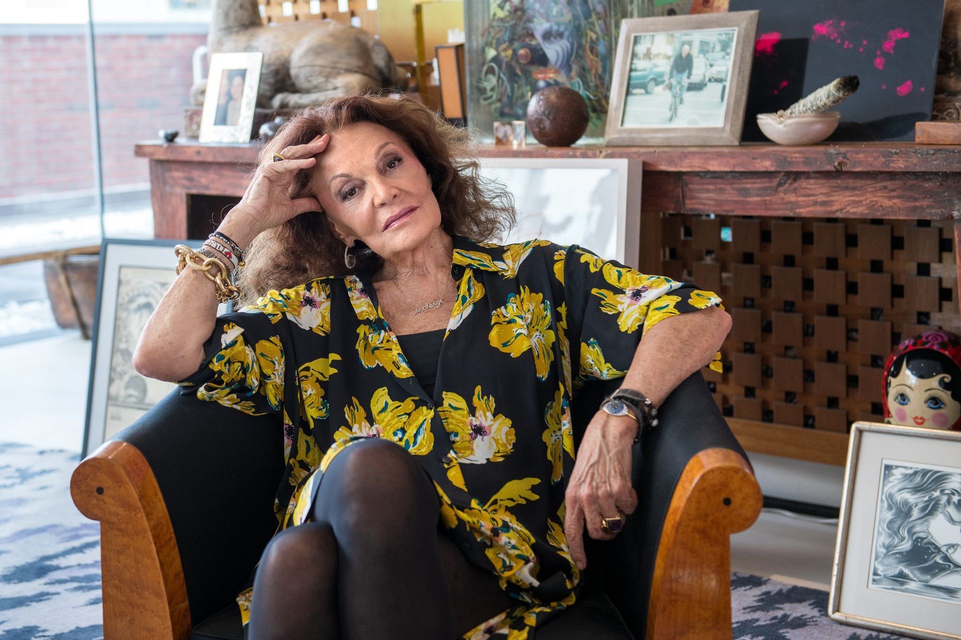 A woman is sitting in a chair with her hand on her head.