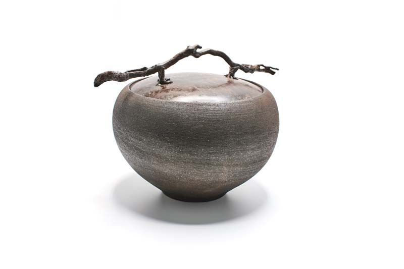 A ceramic container with a branch on top of it