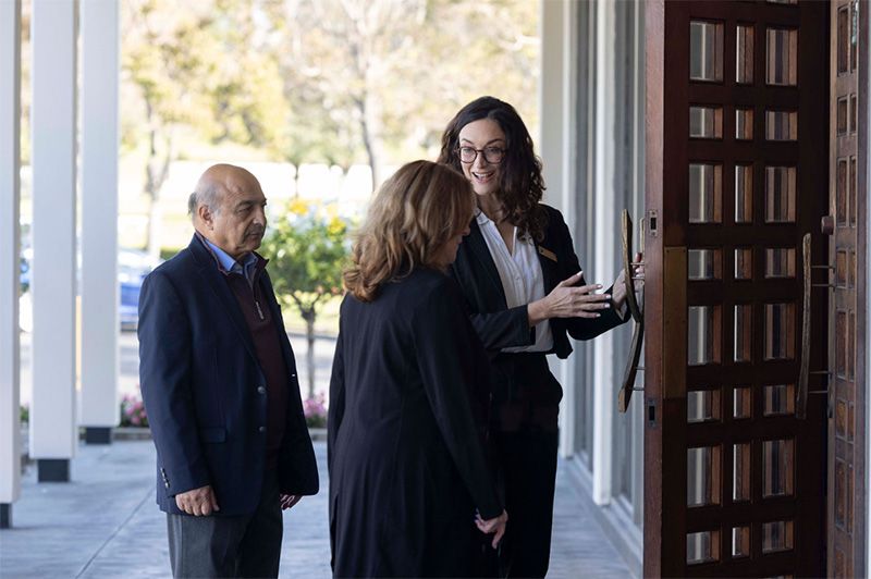 A woman is talking to a man and a woman in front of a door.